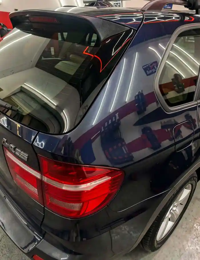 rear view of dark blue bmw suv in detailing shop with ceramic coating and hexagonal water beading