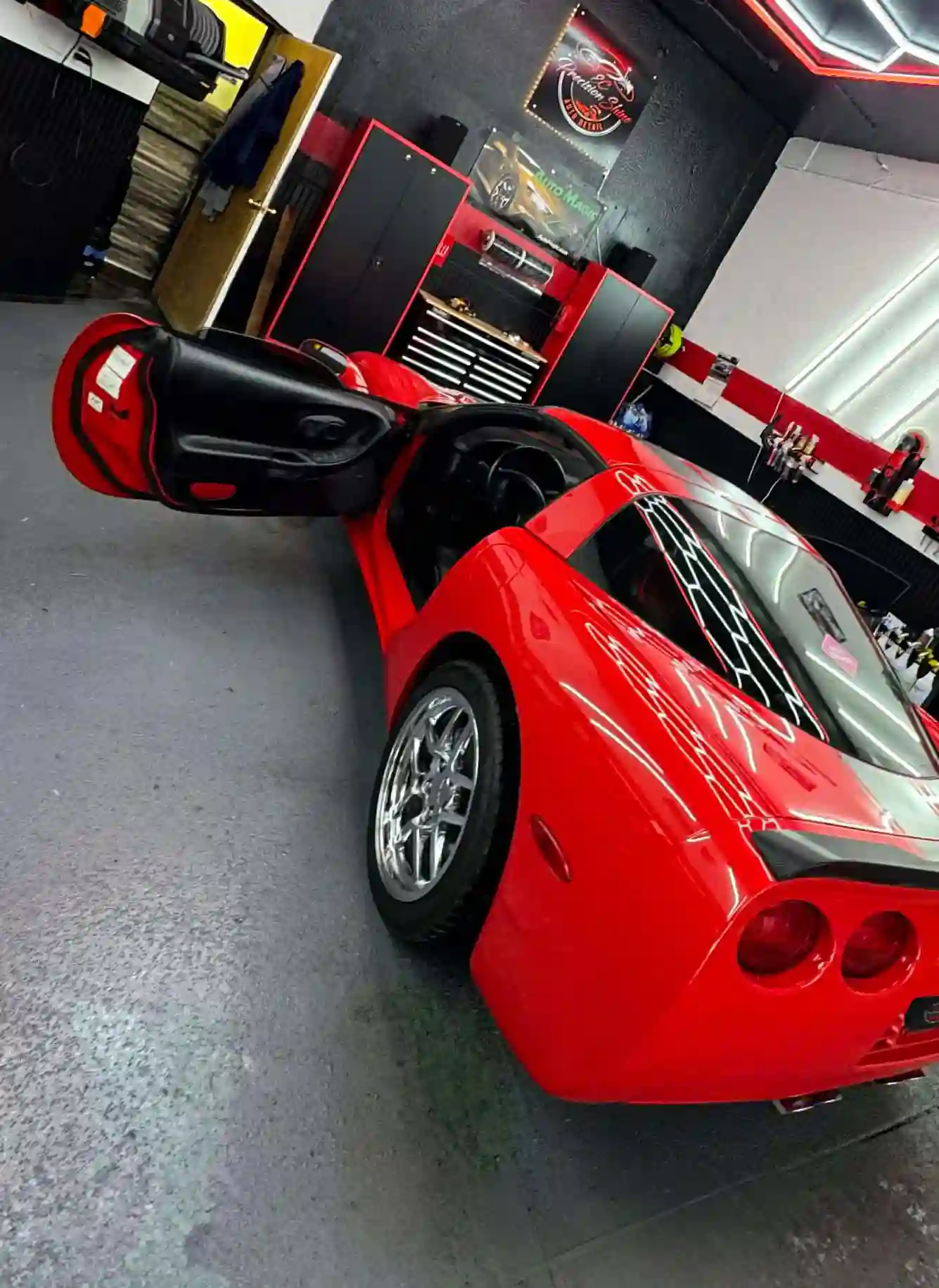 red corvette c5 in detailing shop with hood and doors open under bright led lights
