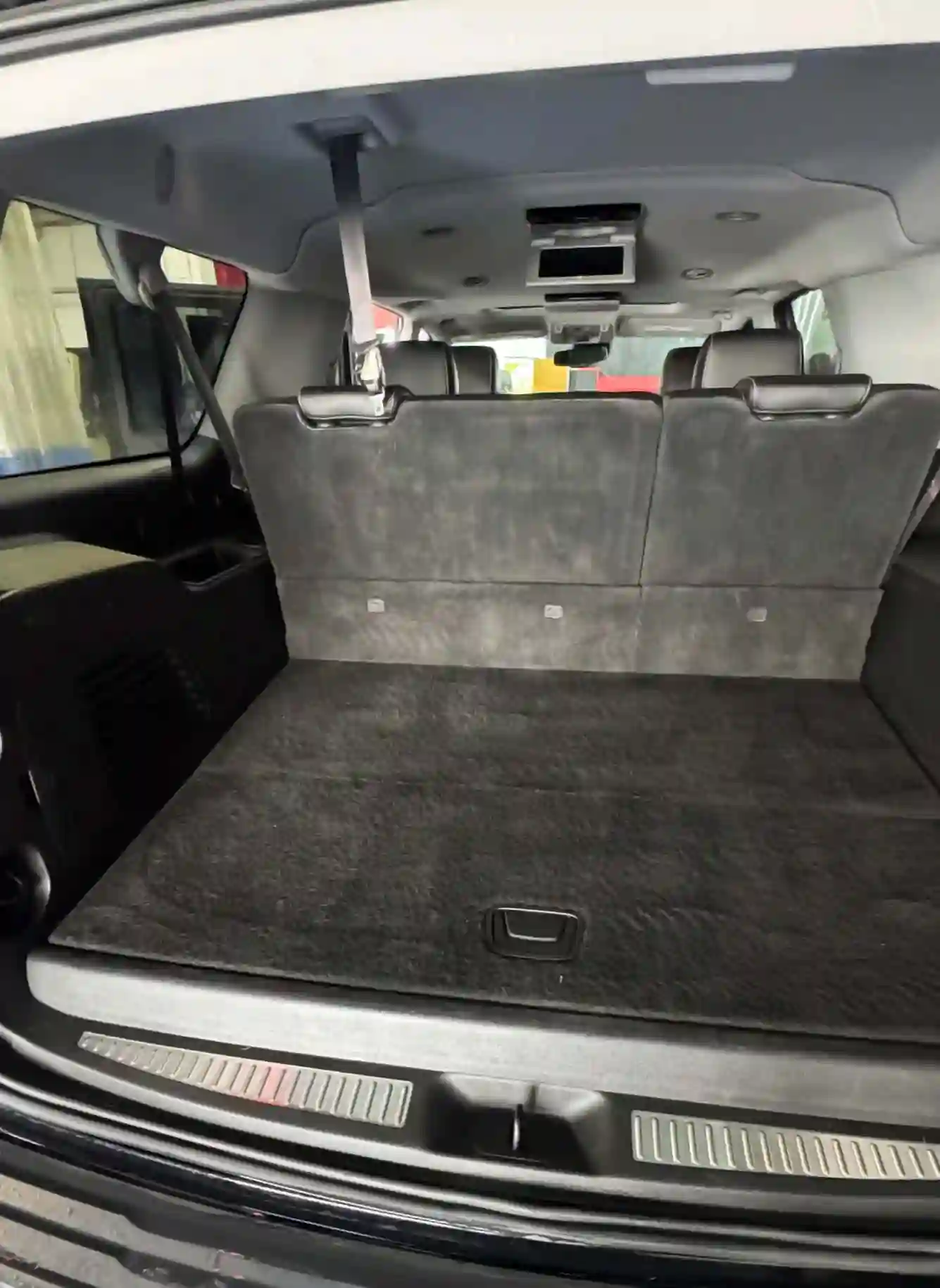 clean suv cargo area with folded third-row seats and spotless black carpet after detailing