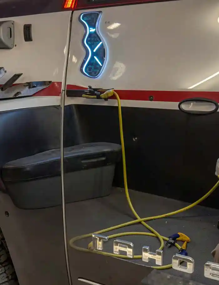 close-up of chevy tahoe door panel with blue neon x light and detailing tools in shop