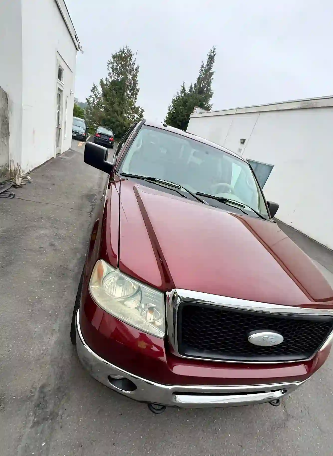 maroon ford f-150 parked in alley with glossy paint and freshly dressed tires