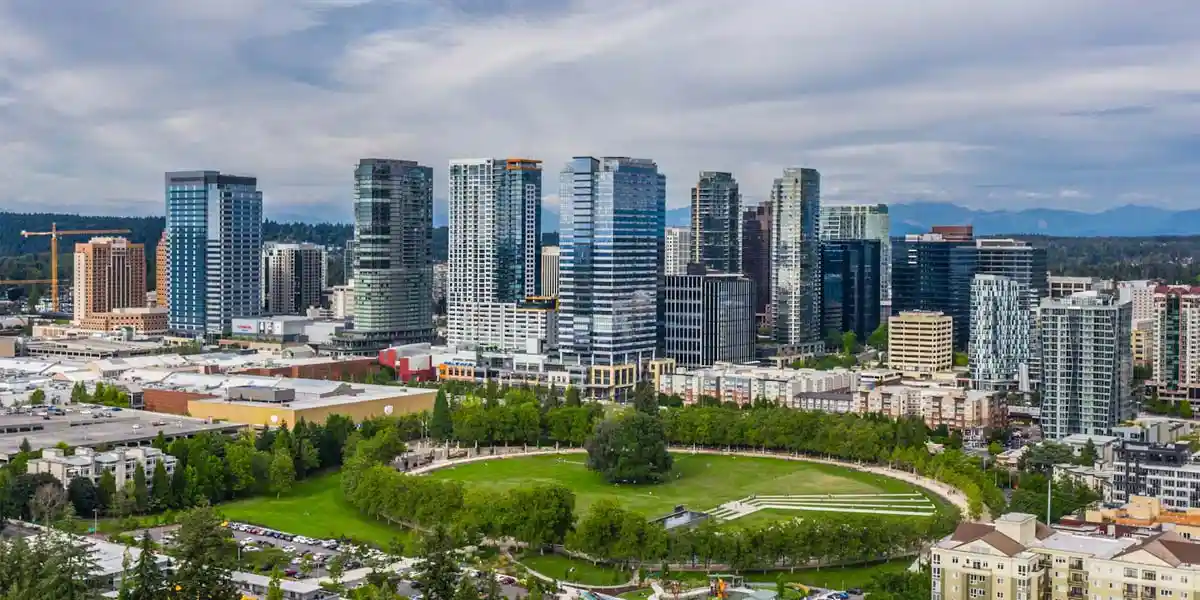 aerial view of bellevue, washington downtown with high-rise towers, park, and distant cascade mountains