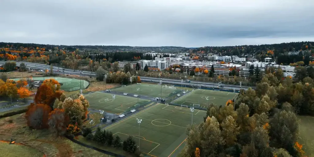 aerial fall view of redmond, washington with soccer fields, autumn trees, and distant cityscape