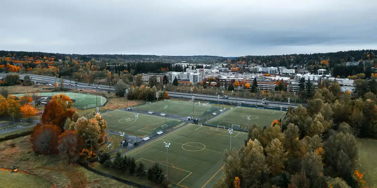aerial fall view of redmond, washington with soccer fields, autumn trees, and distant cityscape