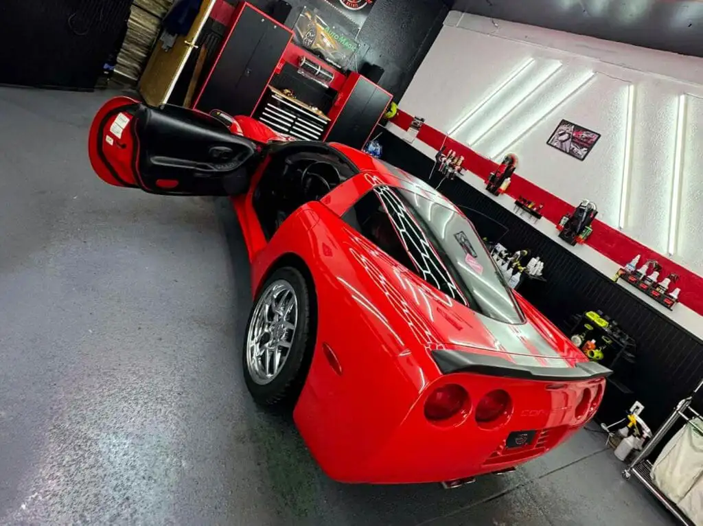 red c5 corvette in precision shine shop with doors open and glossy paint under led lights