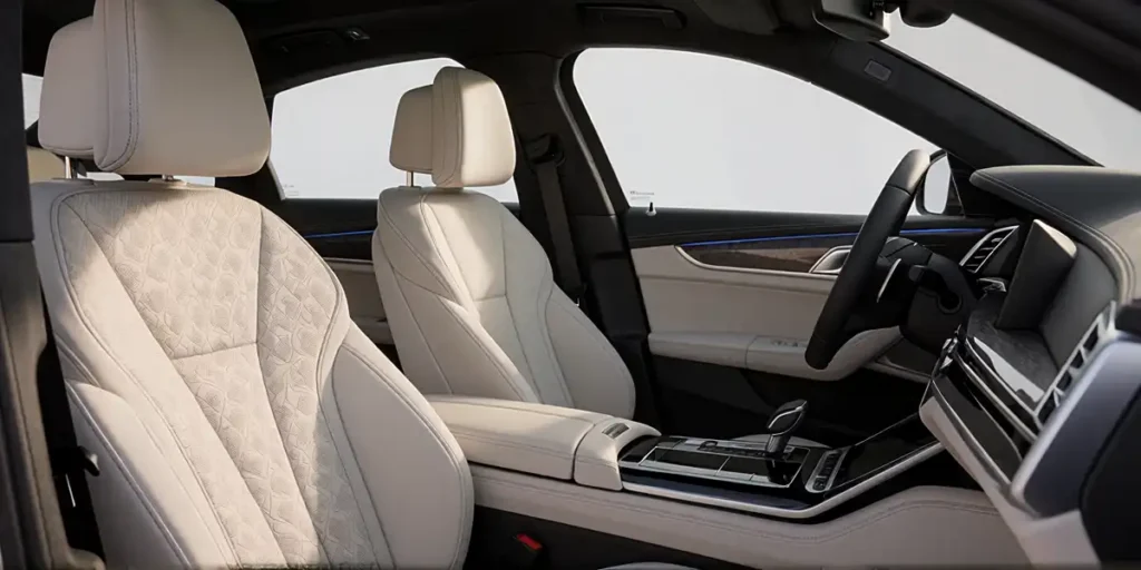interior shot of a luxury sedan showcasing the front passenger and driver seats upholstered in cream-colored quilted leather with precise stitching