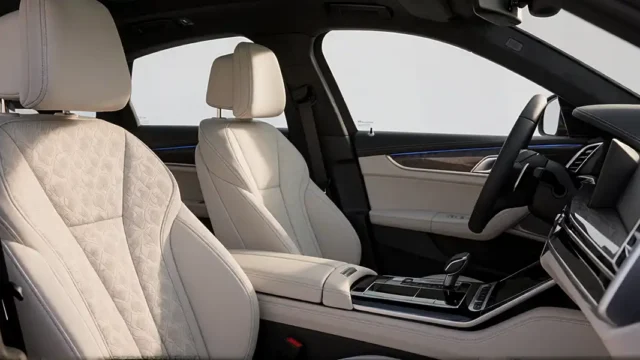 interior shot of a luxury sedan showcasing the front passenger and driver seats upholstered in cream-colored quilted leather with precise stitching